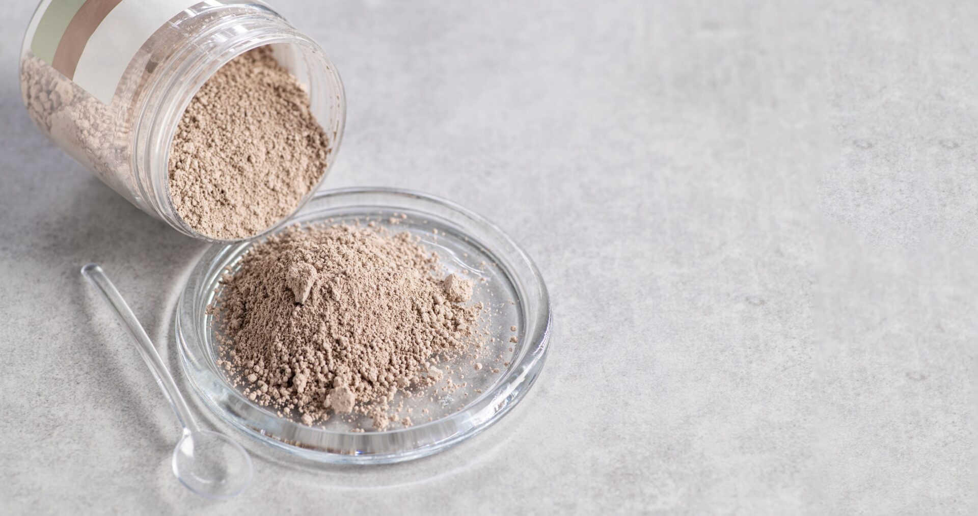 Una ciotola contenente una cipria di colore chiaro su uno sfondo grigio.