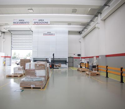 Vista interna di uno stabilimento industriale o magazzino spazioso con bancali e postazioni di lavoro, per la Supply Chain Factory di Makeitalia.