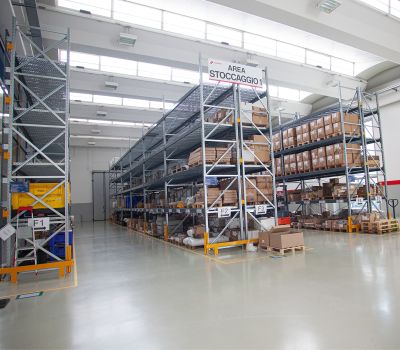 Vista prospettica delle corsie di un grande magazzino con scaffalature e merci.