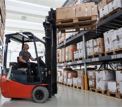 Un carrello elevatore in movimento tra le corsie di un magazzino industriale per la Supply Chain Factory.
